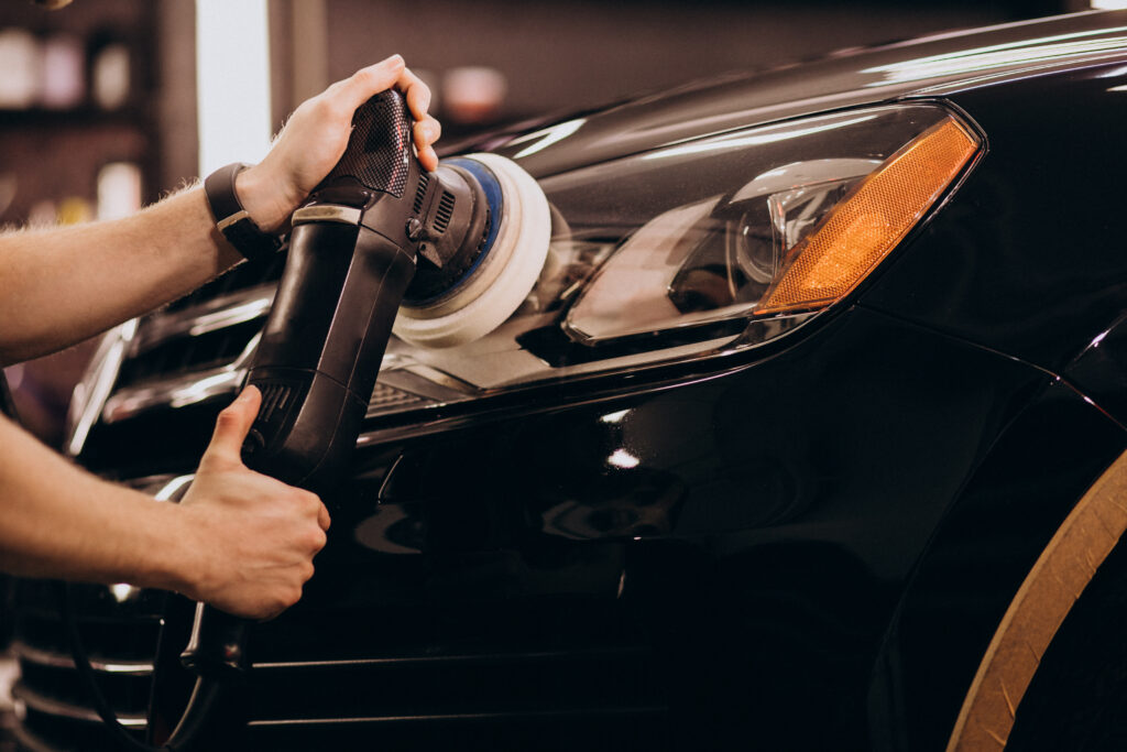 a guy detailing headlight of a car