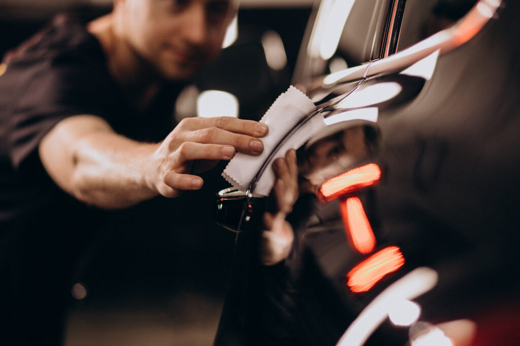 A guy detailing a car with a micro fibber cloth